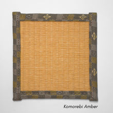 Square tatami coaster with a warm amber coloured igusa centre and a muted grey and olive patterned fabric border.