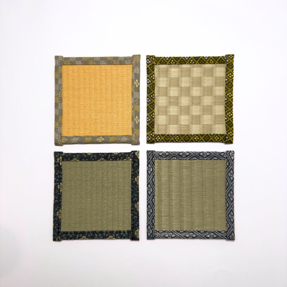 Top down view of four square tatami coasters arranged in a grid, each with a different woven centre and decorative fabric border.